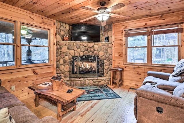 living room featuring ceiling fan, wooden ceiling, light hardwood / wood-style flooring, wood walls, and a fireplace