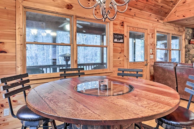 dining space with hardwood / wood-style floors, wood ceiling, wooden walls, and vaulted ceiling