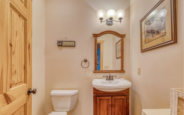 bathroom with toilet, vanity, and a notable chandelier