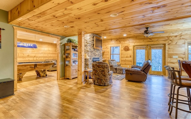 living room featuring light hardwood / wood-style floors, a fireplace, wooden ceiling, ceiling fan, and pool table