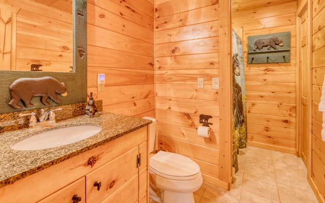 bathroom with wooden walls, tile flooring, toilet, and oversized vanity