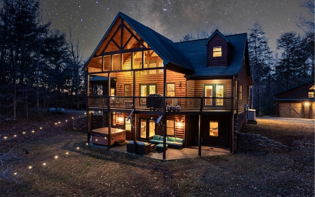 back of house featuring a hot tub, a balcony, a patio area, and a garage