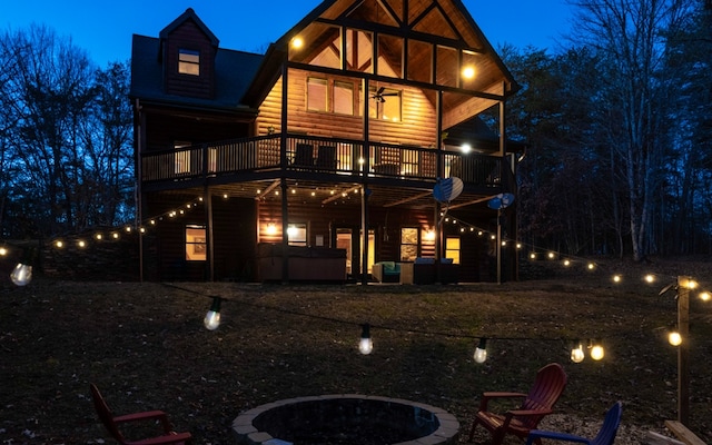 back house at twilight with a balcony and an outdoor fire pit