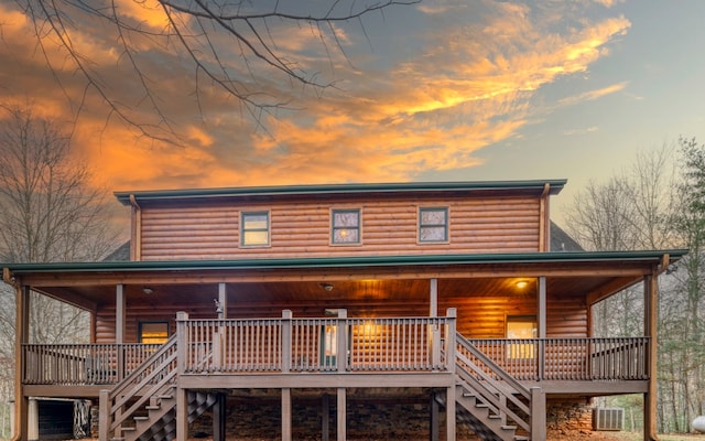 back house at dusk featuring central AC unit and a wooden deck