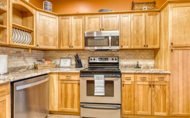 kitchen with appliances with stainless steel finishes, tasteful backsplash, and light stone countertops