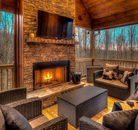 sunroom / solarium featuring a stone fireplace, a wealth of natural light, wooden ceiling, and lofted ceiling