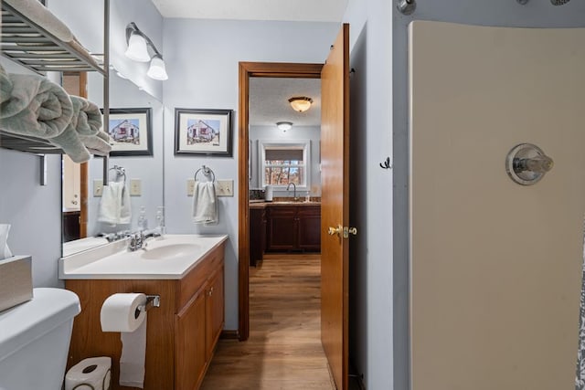 bathroom with hardwood / wood-style flooring, vanity, toilet, and a textured ceiling