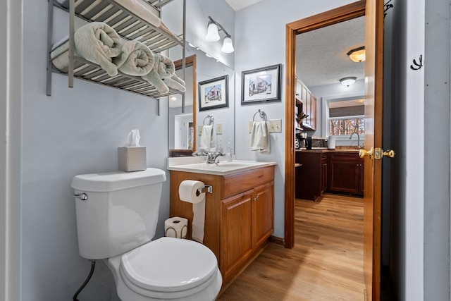 bathroom featuring vanity, toilet, wood-type flooring, and a textured ceiling