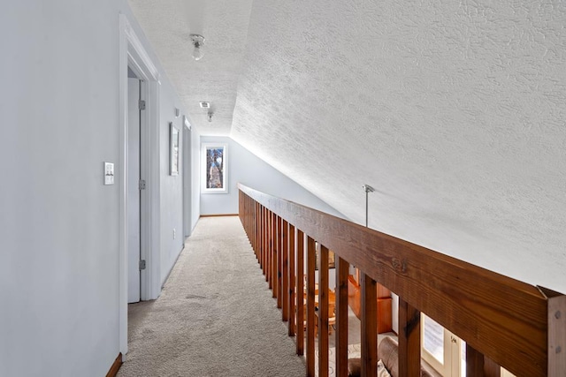 hall featuring lofted ceiling, a textured ceiling, and light carpet