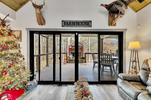 doorway to outside featuring wooden ceiling, high vaulted ceiling, a healthy amount of sunlight, and wood-type flooring