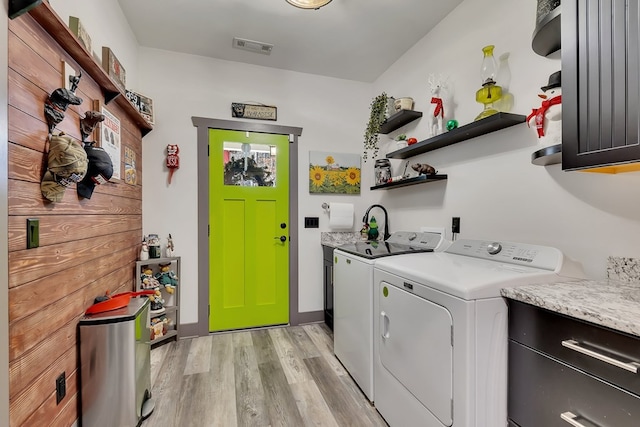 laundry area featuring cabinets, washing machine and dryer, and light hardwood / wood-style flooring