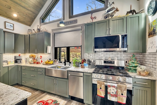 kitchen featuring appliances with stainless steel finishes, green cabinetry, a wealth of natural light, and sink