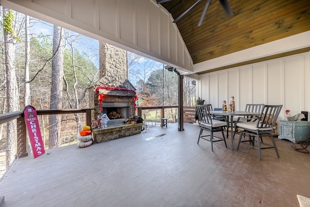 sunroom / solarium with plenty of natural light, an outdoor stone fireplace, lofted ceiling, and wooden ceiling