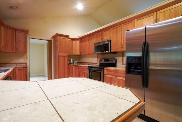 289 12 Point Rd, Blairsville, GA 30512 - kitchen with stainless steel appliances, lofted ceiling, tile countertops, brown cabinetry, and tile patterned flooring