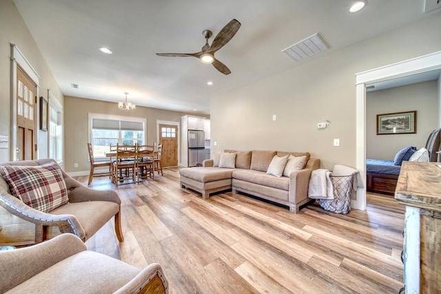 living room with light hardwood / wood-style flooring and ceiling fan with notable chandelier