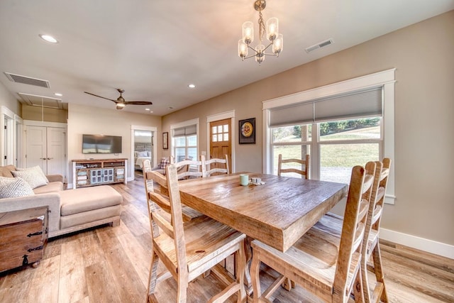 dining room with ceiling fan with notable chandelier and light wood-type flooring