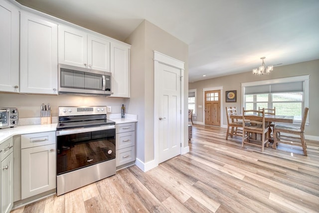 kitchen featuring a notable chandelier, light hardwood / wood-style floors, white cabinetry, and stainless steel appliances