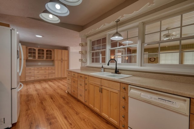 kitchen with light brown cabinets, light countertops, light wood-style floors, white appliances, and a sink