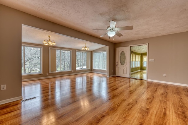 unfurnished living room with a textured ceiling, light wood-style floors, visible vents, and a healthy amount of sunlight