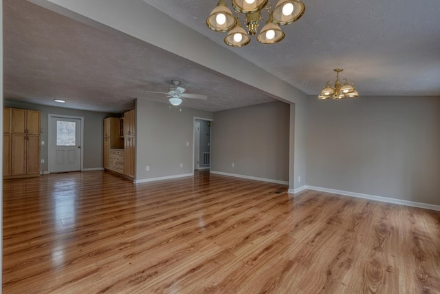 unfurnished living room with a textured ceiling, baseboards, and light wood-style floors