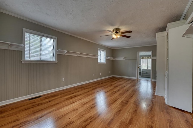 spare room with light wood finished floors, plenty of natural light, a textured ceiling, and a ceiling fan