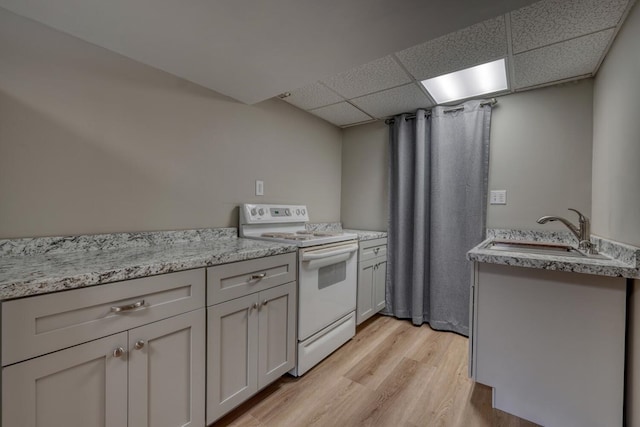 kitchen with a sink, light wood-style flooring, a paneled ceiling, and white electric stove