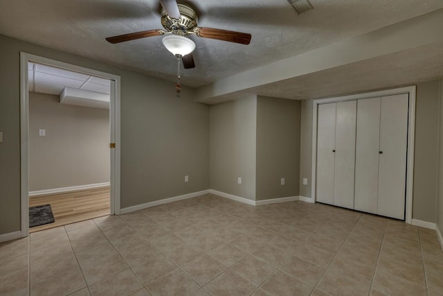 unfurnished bedroom with visible vents, a ceiling fan, a textured ceiling, light tile patterned floors, and baseboards