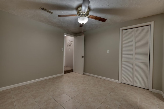 unfurnished bedroom featuring visible vents, baseboards, light tile patterned flooring, a closet, and a textured ceiling