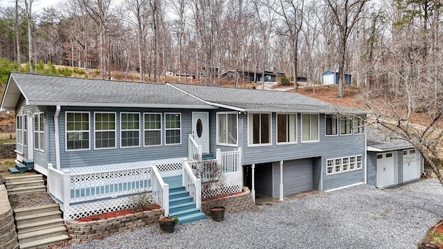 view of front of house with a garage, roof with shingles, and gravel driveway