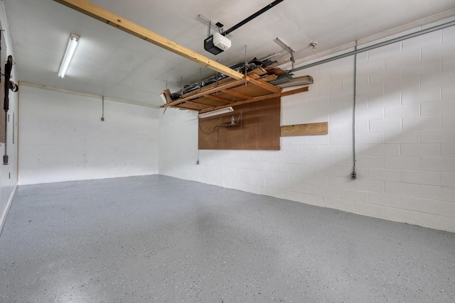 garage featuring concrete block wall and a garage door opener