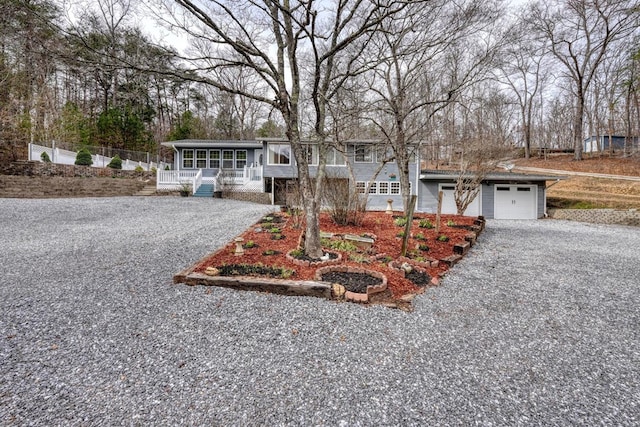 view of front of house with a sunroom, fence, a garage, and driveway