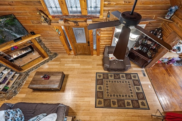 living room featuring ceiling fan, hardwood / wood-style flooring, and rustic walls