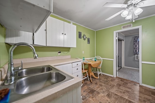 kitchen featuring ceiling fan, white cabinets, crown molding, and sink