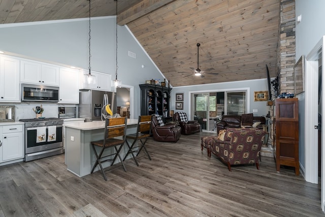 kitchen featuring a kitchen island, decorative light fixtures, white cabinetry, backsplash, and stainless steel appliances