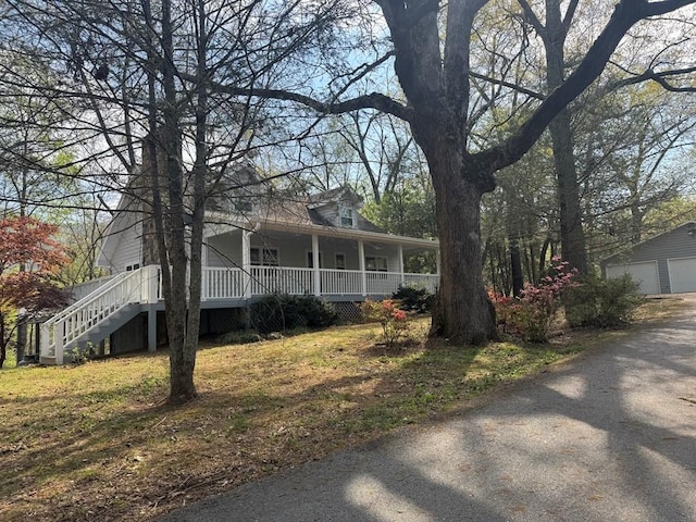 view of front of home with a porch, an outdoor structure, a detached garage, and stairway