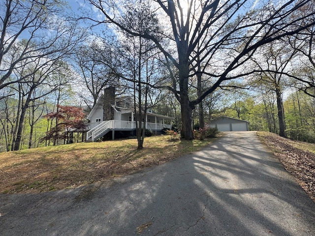 view of front of home with an outdoor structure, a porch, a chimney, and a garage