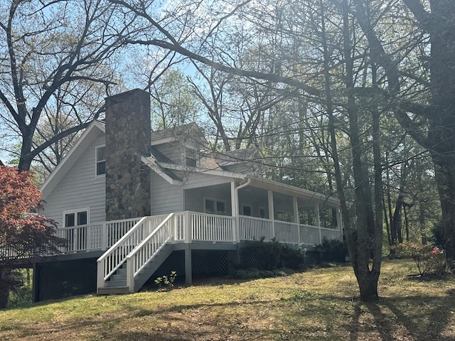 rear view of house with stairs, a yard, a porch, and a chimney