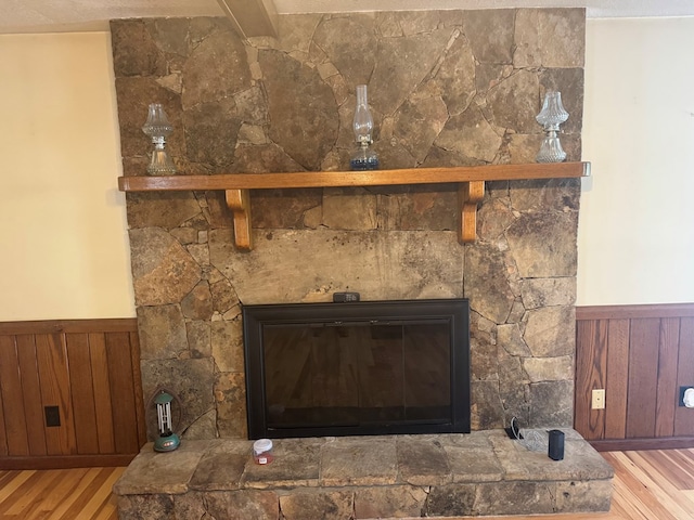 interior details featuring a fireplace, wooden walls, wood finished floors, and wainscoting