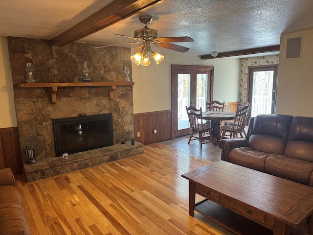 living room featuring hardwood / wood-style floors, a wainscoted wall, a textured ceiling, and a ceiling fan