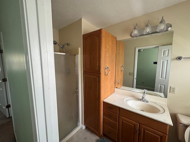 bathroom with tile patterned floors, a textured ceiling, a stall shower, vanity, and toilet