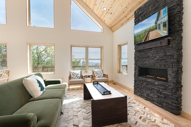 living room featuring a stone fireplace, high vaulted ceiling, light hardwood / wood-style floors, and wooden ceiling