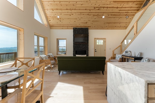 living room with high vaulted ceiling, light wood-type flooring, a wealth of natural light, and wooden ceiling