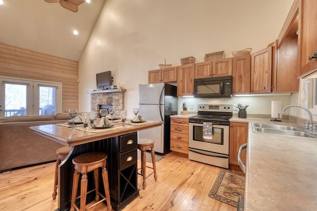 kitchen featuring light countertops, freestanding refrigerator, stainless steel range with electric cooktop, a sink, and black microwave