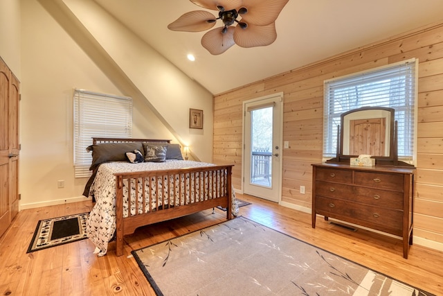 bedroom featuring access to exterior, vaulted ceiling, hardwood / wood-style floors, and wood walls