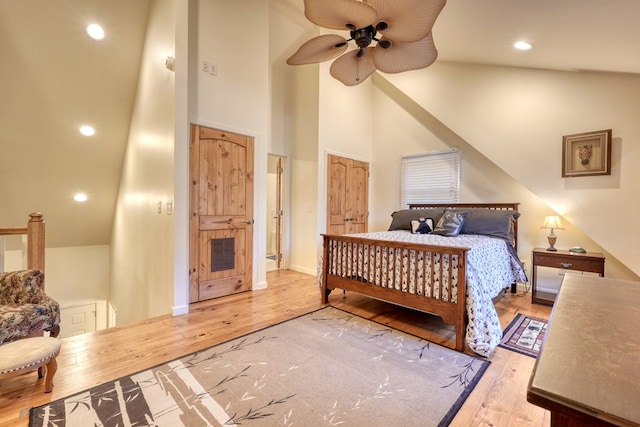 bedroom featuring ceiling fan, recessed lighting, wood finished floors, visible vents, and a towering ceiling