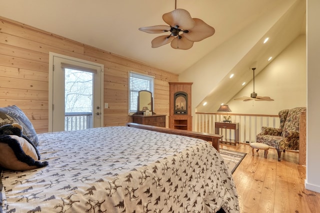 bedroom with access to exterior, vaulted ceiling, hardwood / wood-style flooring, and wooden walls