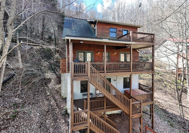 rear view of house with stairs, a shingled roof, and a deck