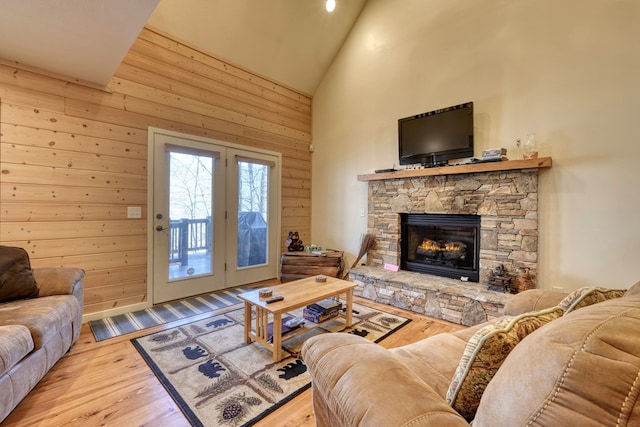 living room with wood walls, a fireplace, high vaulted ceiling, and wood finished floors