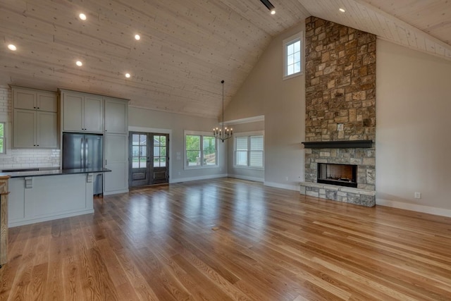 unfurnished living room featuring light wood finished floors, an inviting chandelier, high vaulted ceiling, a fireplace, and wooden ceiling