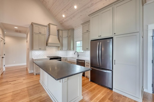 kitchen with a sink, visible vents, custom exhaust hood, a kitchen island, and appliances with stainless steel finishes